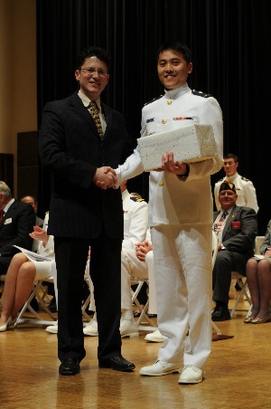 Cdr. Gregory Johnson, USCG (l), congratulates Cadet First Class Manatchai Fangsuwannark, USCG, for winning the AFCEA award at the May scholarship awards ceremony.
